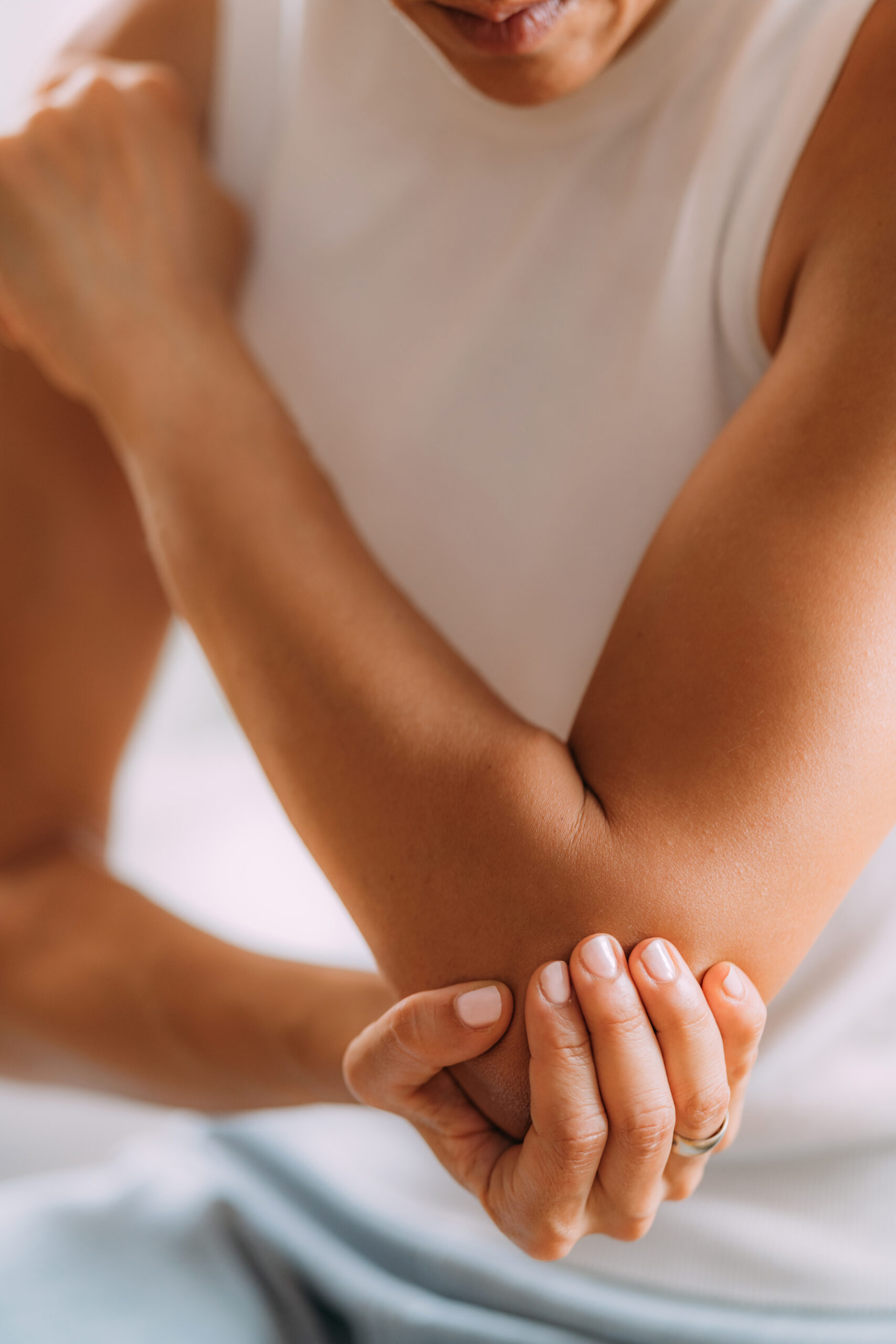 Oberkörper einer jungen Frau, die sich den schmerzenden Ellenbogen hält - Akupunktur als alternative Therapiemethode